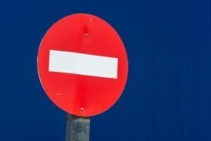 Close-up of a red no entry traffic sign against a vivid blue background.