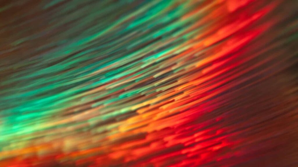 Choosing the Right Internet Service for Your Business (Cable vs. Fiber vs. 5G) Bright, vibrant digital art featuring holographic fiber optic strands in green, red, orange, and yellow.