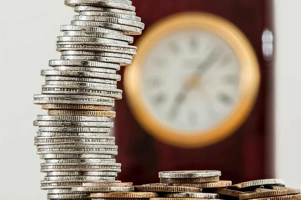 Coin stack with time-saving concept, gold and silver coins, clock, financial growth, wealth, investment strategy.