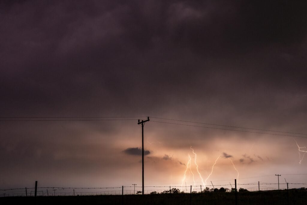 Storm clouds and lightning bolts during a thunderstorm over a rural area.
