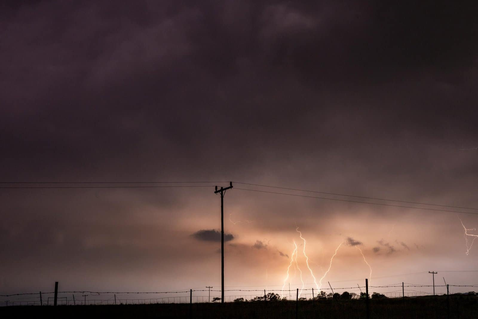 Storm clouds and lightning bolts during a thunderstorm over a rural area.
