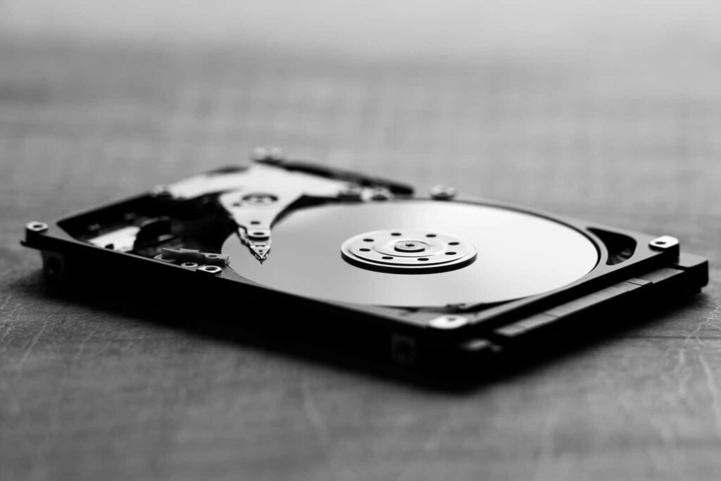 Close-up of a disassembled hard disk drive in black and white, highlighting internal components and magnetic platter.